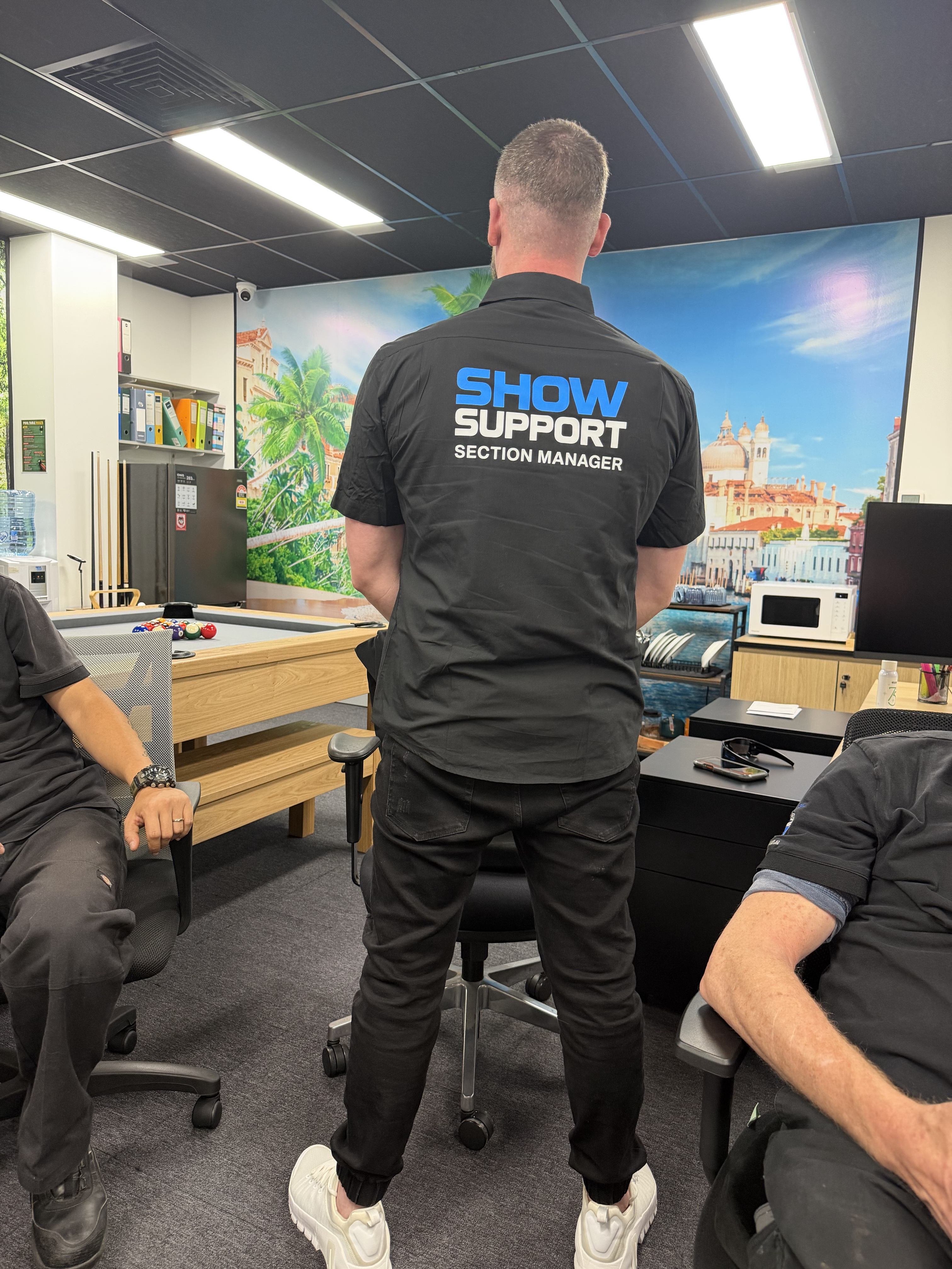 Sam Davis displaying the back of the Show Support Section Manager uniform